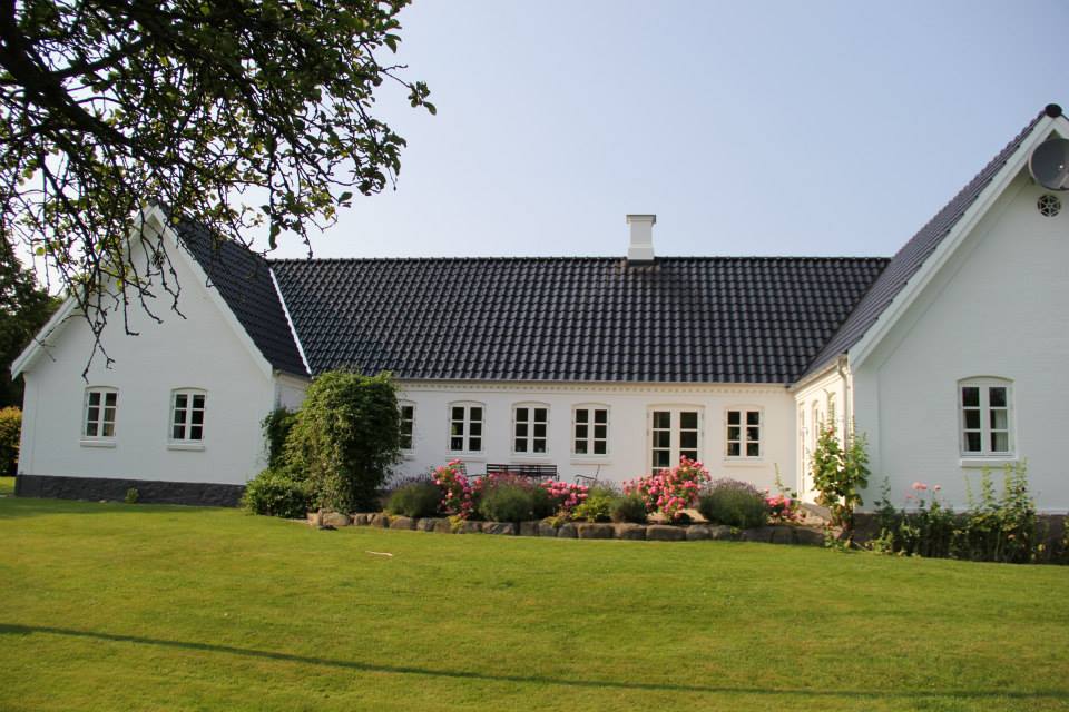 Hvid bondegård med have og grøn græsplæne